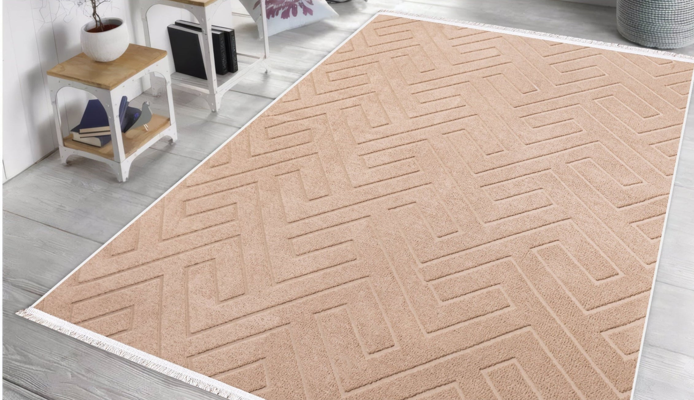 Beige geometric-patterned rug on a wooden floor with a white wall and small table in the background.