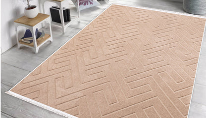 Beige geometric-patterned rug on a wooden floor with a white wall and small table in the background.